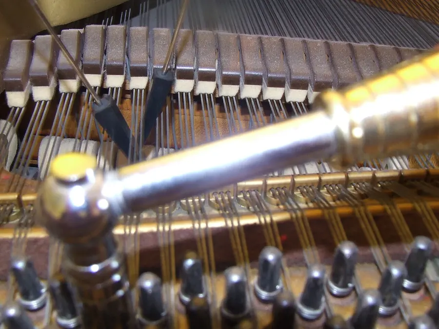 Tuning hammer and rubber mutes resting on piano strings